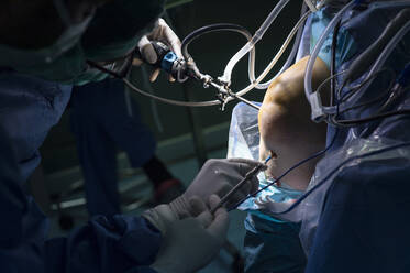Männlicher orthopädischer Chirurg bei einer Operation am Knie eines Patienten auf der Intensivstation - JCMF01702