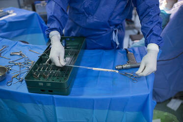 Männlicher Orthopäde bereitet Kniesehne im Operationssaal vor - JCMF01706