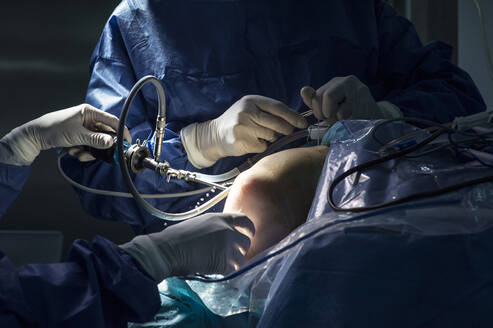 Männliche Chirurgen bei einer Knieoperation in der Notaufnahme eines Krankenhauses - JCMF01708