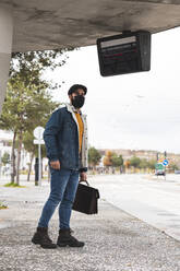 Commuter wearing hat waiting for bus during COVID-19 - JAQF00025