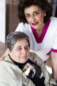 Pflegerin mit behinderter Frau, die ein Meerschweinchen im Rehabilitationszentrum hält - LJF02005