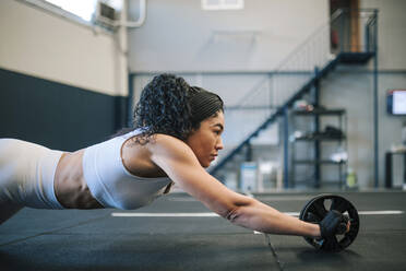 Selbstbewusste Sportlerin beim Training mit dem Bauchtrainingsrad im Fitnessstudio - GRCF00573