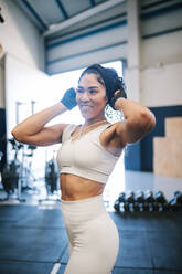 Lächelnde Sportlerin, die im Fitnessstudio ihr Stirnband verstellt und dabei wegschaut - GRCF00585