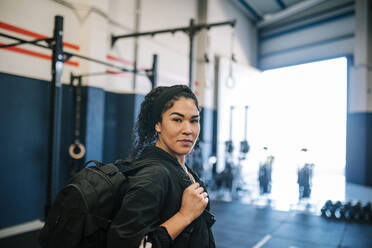 Confident female athlete with backpack in gym - GRCF00586