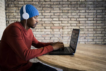 Männlicher Unternehmer sitzt am Tisch und arbeitet am Laptop - RCPF00534