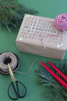 Schere, Schnur und Wortsuchrätsel auf verpacktem Weihnachtsgeschenk - GISF00714
