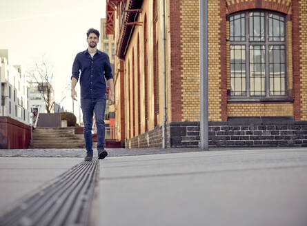 Businessman walking on footpath in city - RHF02571