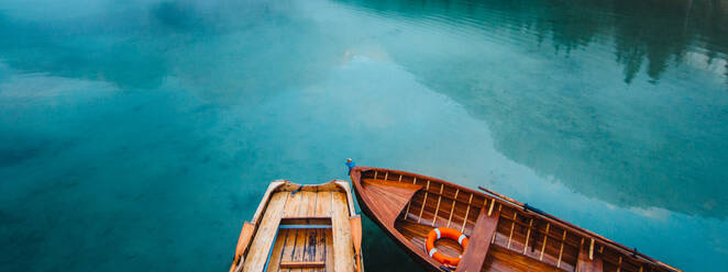 Von oben Holzboot mit Paddeln schwimmt auf türkisfarbenen Wasser der ruhigen See auf dem Hintergrund der majestätischen Landschaft des Hochlandes - ADSF19354