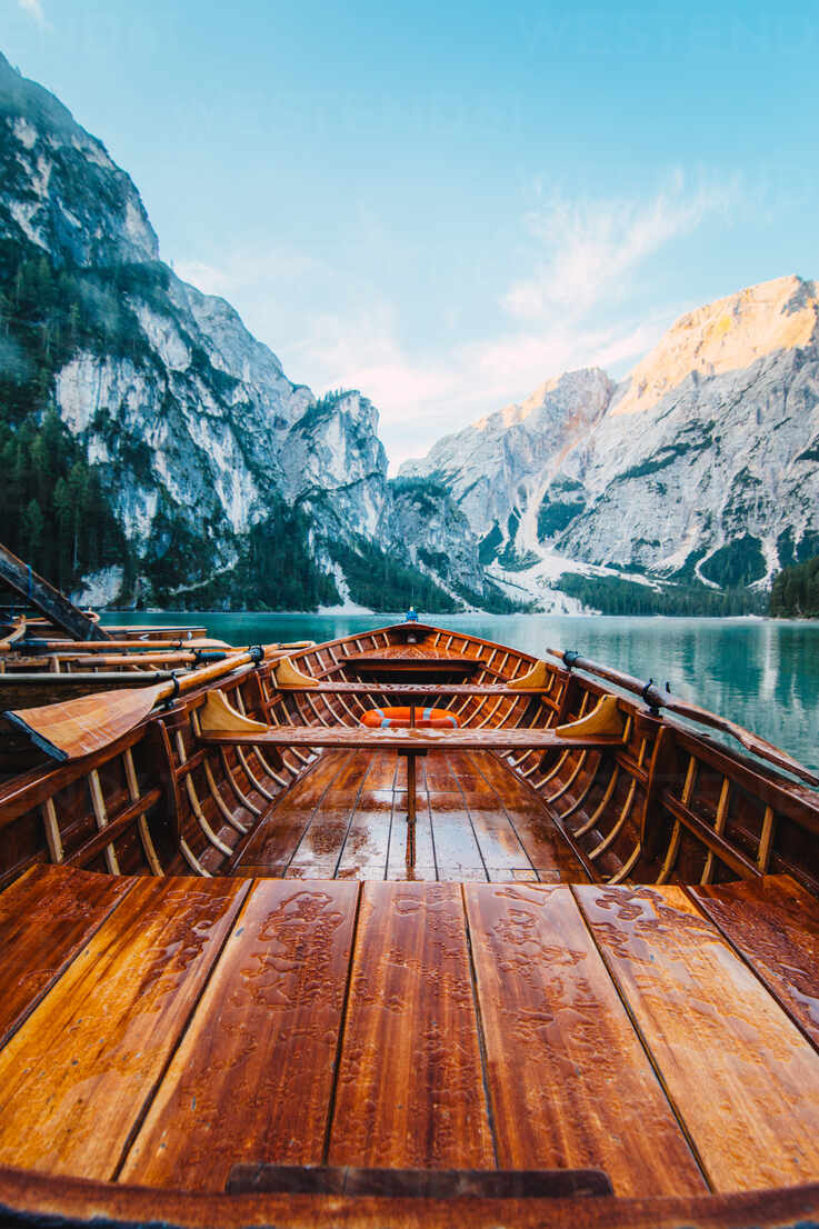 Wooden boat with paddles floating on turquoise water of calm lake