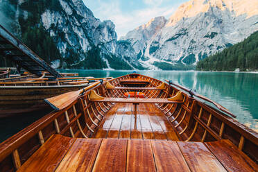 Holzboot mit Paddeln schwimmt auf türkisfarbenem Wasser der ruhigen See auf dem Hintergrund der majestätischen Landschaft des Hochlandes - ADSF19361