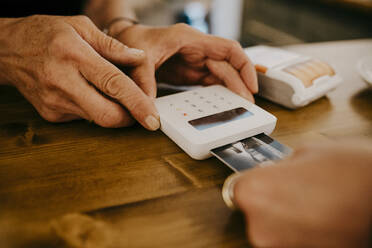 Abgeschnittene Hand eines Kunden, der mit seiner Kreditkarte in einem Café bezahlt - MASF21034