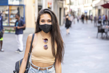 Junge Frau mit Gesichtsmaske auf der Straße in der Stadt - WPEF03827