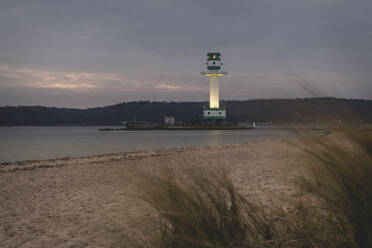 Deutschland, Schleswig-Holstein, Friedrichsort, Sandstrand in der Morgendämmerung mit Leuchtturm im Hintergrund - KEBF01697