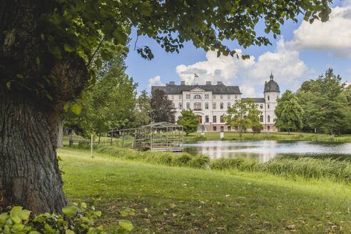 Deutschland, Schleswig-Holstein, Fargau-Pratjau, Salzau fließt durch einen öffentlichen Park mit Gut Salzau im Hintergrund - KEBF01701