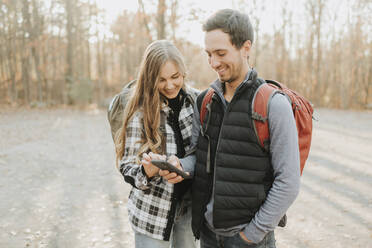 Junges Paar benutzt Smartphone bei Herbstwanderung - SMSF00471