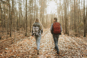 Young couple hiking with backpacks in autumn forest - SMSF00472
