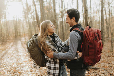 Junges Paar, das sich bei einer Herbstwanderung im Wald umarmt - SMSF00474