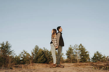 Young couple holding hands while standing back to back - SMSF00502