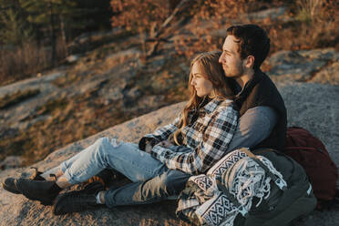 Young couple sitting together on rocky surface during autumn hike - SMSF00513