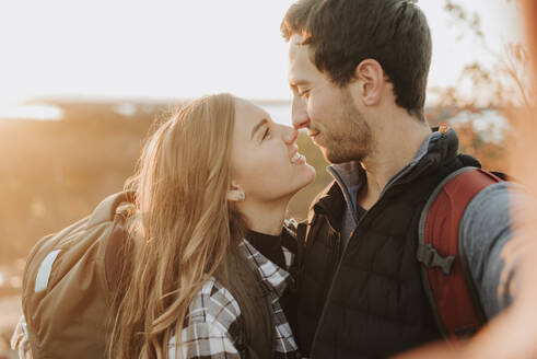 Porträt eines jungen Paares, das sich bei einer Herbstwanderung liebevoll ansieht - SMSF00517