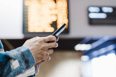 Nahaufnahme eines Mannes, der ein Mobiltelefon benutzt, während er in einer U-Bahn-Station steht - EBBF01897