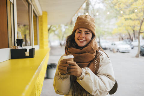 Happy woman at street cafe with disposable coffee cup during autumn stock photo