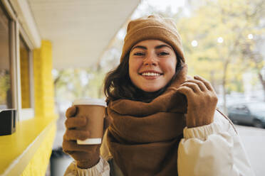 Smiling woman having coffee at street cafe during autumn - OYF00303
