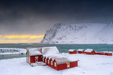 Wintersonnenuntergang über dem arktischen Meer und Fischerhütten im Schnee, Sorvaer, Insel Soroya, Hasvik, Troms og Finnmark, Norwegen, Skandinavien, Europa - RHPLF18546