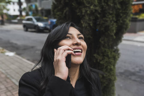 Happy woman talking on smart phone in city stock photo