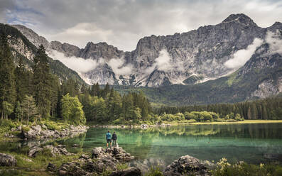 Man and woman standing by lake in mountain landscape - MSUF00481