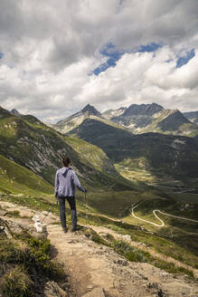 Frau mit Hund in Landschaft stehend, Blick auf Bergpass - MSUF00496