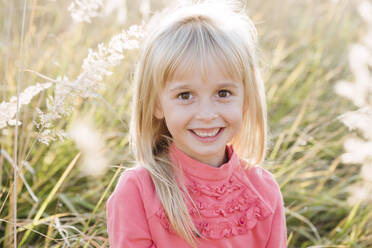 Lächelndes süßes Mädchen in landwirtschaftlichem Feld - EYAF01421