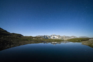 Starry sky over Galenstock mountain reflected in the pristine Mittleres Schwarziseeli lake, Furka Pass, Canton Uri, Switzerland, Europe - RHPLF18722