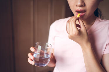 Crop unerkennbar weiblich mit Glas frisches Wasser Einnahme von gelben Vitamin-Pille während der Darstellung gesunden Lebensstil Konzept - ADSF19473
