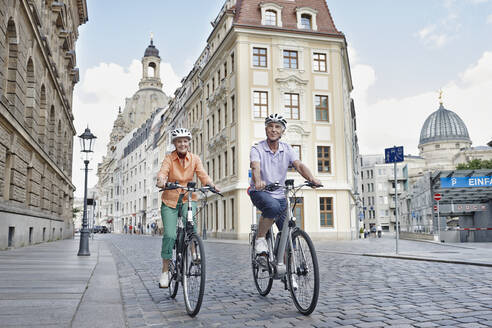 Ältere Touristen auf einem Elektrofahrrad vor der Frauenkirche in Dresden, Deutschland - RORF02569