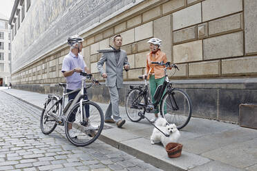 Explorers with electric bicycle looking at man walking with puppy on footpath at Dresden, Germany - RORF02571