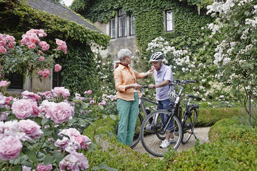 Senior man smelling rose flower while standing by woman at park in Dresden. Germany - RORF02575