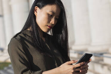 Confident businesswoman using smart phone during sunny day - PNAF00370