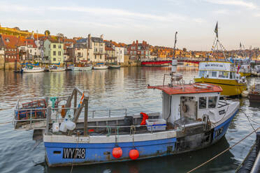 Blick auf Häuser am Flussufer und Fischerboote auf dem Fluss Esk bei Sonnenuntergang, Whitby, Yorkshire, England, Vereinigtes Königreich, Europa - RHPLF18754