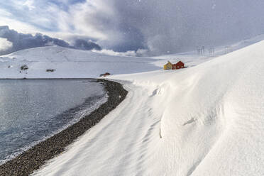 Schneefall auf den einsamen Holzhäusern mit Blick auf das arktische Meer, Skarsvag, Nordkapp, Troms og Finnmark, Nordnorwegen, Skandinavien, Europa - RHPLF18779