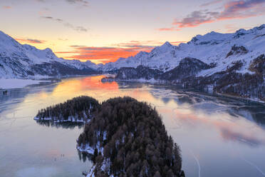 Luftaufnahme des brennenden Himmels bei Sonnenuntergang auf dem gefrorenen Silsersee und schneebedeckten Bergen, Malojapass, Kanton Graubünden, Schweizer Alpen, Schweiz, Europa - RHPLF18947