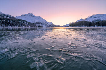 Im Eis gefangene Äste unter der gefrorenen Oberfläche des Silsersees bei Sonnenuntergang, Engadin, Kanton Graubünden, Schweiz, Europa - RHPLF18952