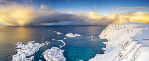 Brennender Himmel bei Sonnenaufgang über dem kalten Meer und Sorvaer Dorf mit Schnee bedeckt, Soroya Island, Hasvik, Troms og Finnmark, Arktis, Norwegen, Skandinavien, Europa, lizenzfreies Stockfoto