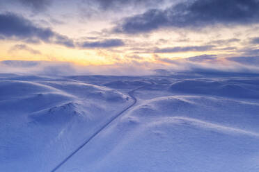 Arktischer Sonnenuntergang über dem Tanafjordveien leere Straße über die verschneiten Berge nach Schneesturm, Tana, Troms og Finnmark, Arktis, Norwegen, Skandinavien, Europa - RHPLF18972