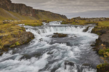 Eine klassische isländische Landschaft, ein Fluss, der am Fuße einer Klippe entlangfließt, Der Fluss Fossalar, in der Nähe von Kirkjubaejarklaustur, Island, Polarregionen - RHPLF19020