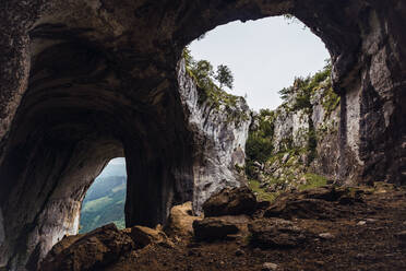 Malerischer Blick auf eine borstige Höhle und Berge in der Nähe wachsender Bäume im Baskenland - ADSF19552