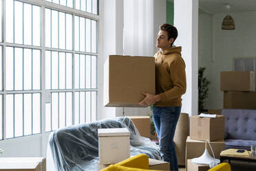 Junger Mann trägt Kiste beim Umzug in eine neue Wohnung - GIOF10259