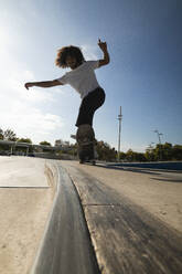 Young man practicing on skateboard at skateboard park - PNAF00376