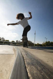 Junger Mann beim Üben auf dem Skateboard im Skateboardpark - PNAF00376