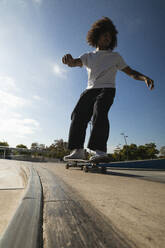 Sportsman practicing while skateboarding on skate at skateboard park - PNAF00377